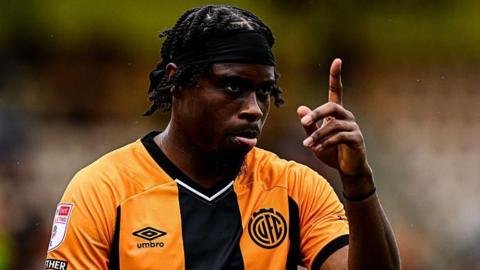 Pelly Ruddock Mpanzu raises his left index finger to the sky during a game