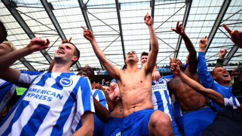 Football fans celebrate. Some of them have their tops off. 