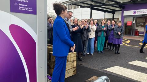 A group of people gathered outside the Practice Plus Group Hospital in Shepton Mallet. They are clapping their hands as they celebrate the opening of the new unit