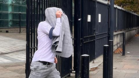 Christopher Morrow leaving Laganside Court covering his head with his jacket