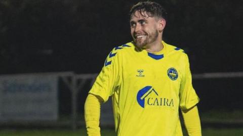 Jack Badger, smiling while playing football in a yellow Abingdon United shirt 