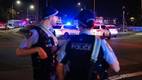 Police officers at night with police vans in the background.