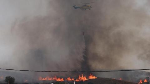 A firefighting helicopter dumps water over a wildfire in Los Gallardos, Almeria, Spain, July 10