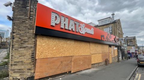 An boarded up building with Phat Spuds signage on it 