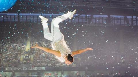 Millie Harvey is upside down in mid-air during her performance at the Take That concert at the Ethihad Stadium
