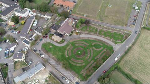 An aerial view above of fields surrounding buildings, central one of a crematorium in Jersey.