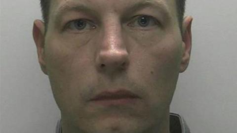 A mugshot of Anthony Redmond with short dark hair and a white-ish background.