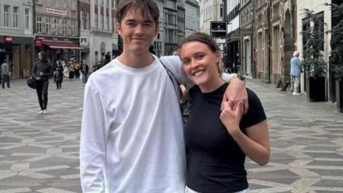 Maisie Roberts, who has her hair tied back and is in a black top, with boyfriend Bertie Kinnings, who is in a white T-shirt and has his arms around her.