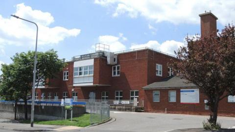 External view of the two-storey red-brick Weymouth Community Hospital with a road running along the outside