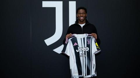 Jonathan David holds up a black and white Juventus shirt
