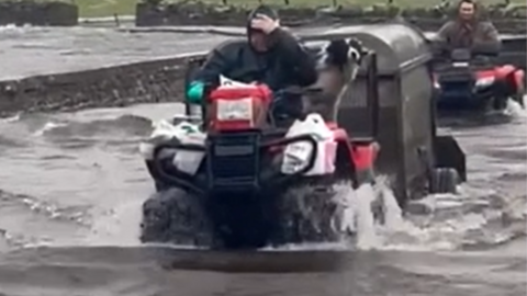Farmers driving through flood water in the Yorkshire Dales on quad bikes