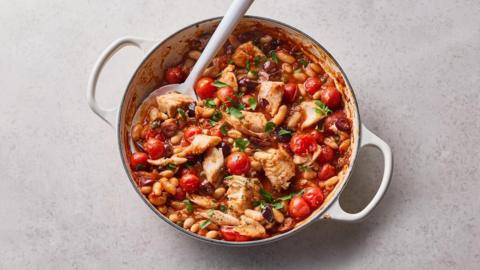 White fish and cannellini bean puttanesca one-pot bake on a loght grey background