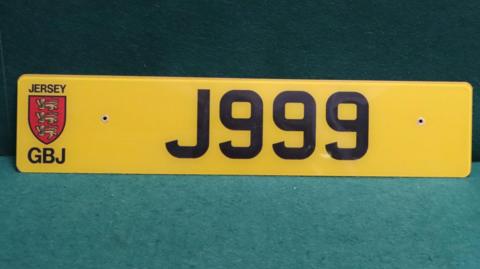 A yellow Jersey license plate with the numbering and lettering reading J999 which matches the one shown in the original series of the children's TV show Fireman Sam. 