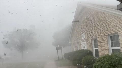 A house surrounded by cloud and debris flying around