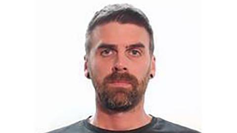 A police mugshot of Christopher Malcolm, a man with a beard looking at the camera.