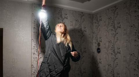 Yulia hangs a light in her home