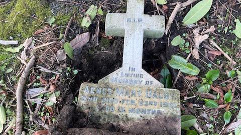 A cross headstone pulled out of the ground