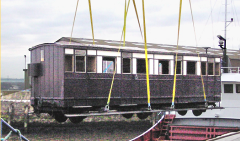 A vintage train carriage being craned 