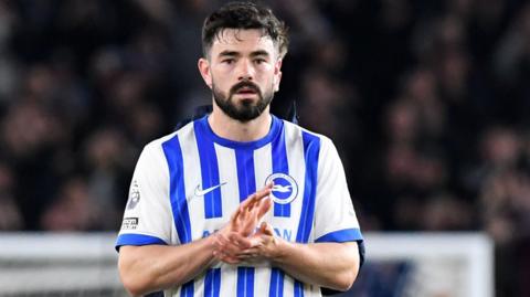 Eiran Cashin applauds Brighton fans following his debut against Aston Villa