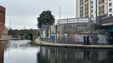 Two officers stood on a canal path near a turning basin