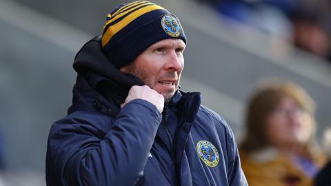 Michael Appleton adjust the collar of his puffer coat as he watches on from the touchline