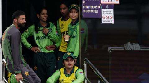 Pakistan players and staff looking out onto the ground from the dressing room
