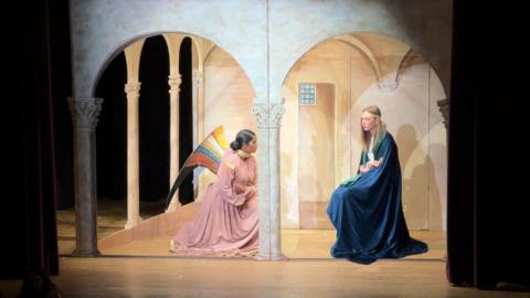 Two female students, one dressed as an angel, the other as the Virgin Mary on stage recreating a nativity scene for the Tableaux.  