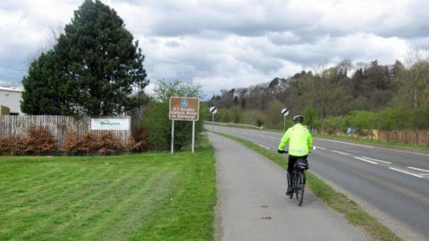 Someone on a bike cycling along a pathway next to the A7 in the Borders