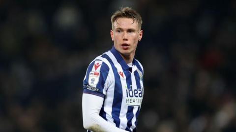 Footballer Torbjorn Heggem during a match for West Bromwich Albion, he wears a blue and white striped Albion shirt with an "Ideal Heating" sponsor on the front. 