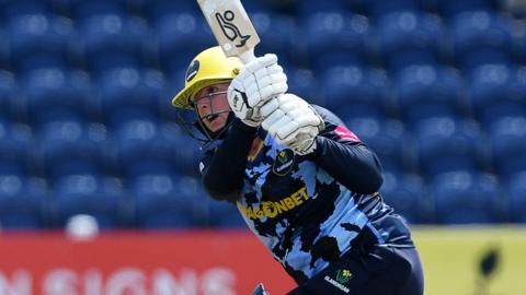 Lauren Parfitt in blue Glamorgan kit and wearing a helmet swings the bat