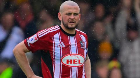 Pierce Sweeney in action for Exeter City in their red and white striped home shirt