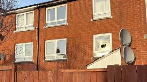 Red brick building with two smashed windows