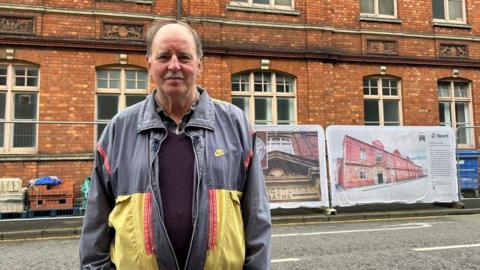 Gerry Hannon, member of Friends of the Health Hydro, stands outside the building which is covered in scaffolding.