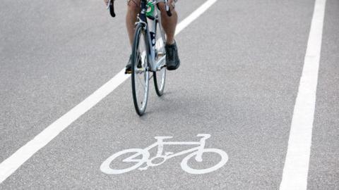A stock image of a person riding a bicycle over a bike path symbol. 