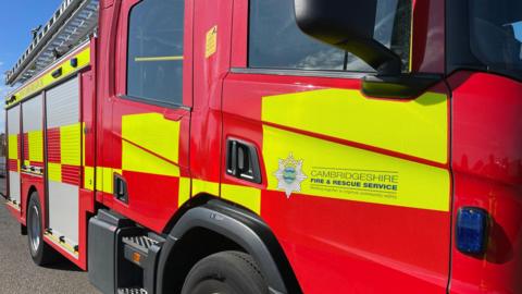 A red fire engine with Cambridgeshire Fire and Rescue Services branding set on a yellow background.