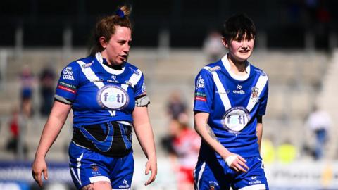 Raiders' players Kelly Friend and Blossom Howell walk disconsolately back towards their own half.