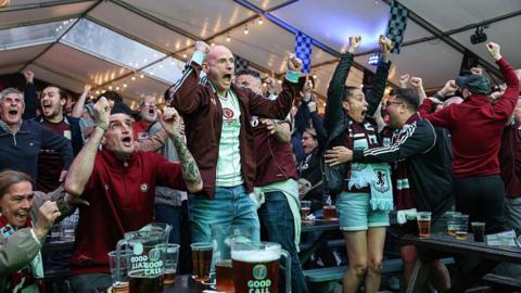 Supporters of Aston Villa cheer after their team's first goal, as they watch the UEFA Europa League final football match between SC Freiburg and Aston Villa on a large TV screen at the Witton Arms pub near Villa Park in Birmingham, central England on May 20