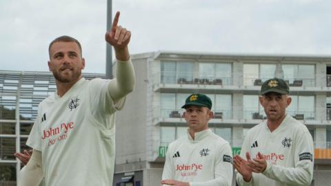 Fergus O'Neill points to someone in the crowd as he leaves the pitch with two team-mates behind him, both applauding
