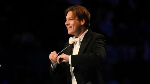 A conductor performing at the Proms