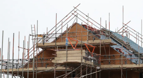 A generic image of a house being partially constructed. The red brick house has scaffolding around it.