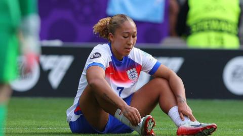England forward Lauren James sits on the turf looking disappointed during Euro 2025
