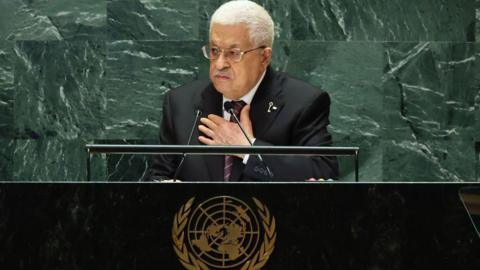 Picture shows Mahmoud Abbas - an older man with white hair, glasses and a greying moustache dressed in a suit and tie - speaking at the United Nations General Assembly in New York. He is standing behind a desk that bears the UN logo.