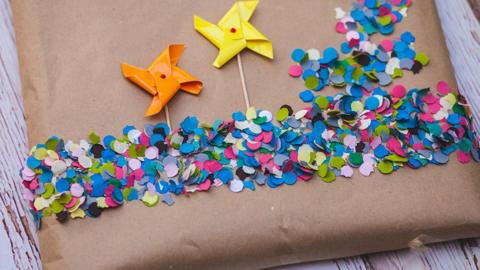 Eco-friendly Christmas present wrapping with brown paper, colourful circles of paper and paper windmills.