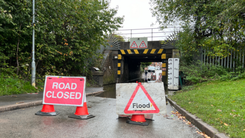 An image of a railway bridge over a flooded Church Hill Road in Thurmaston, with road closure signs. 