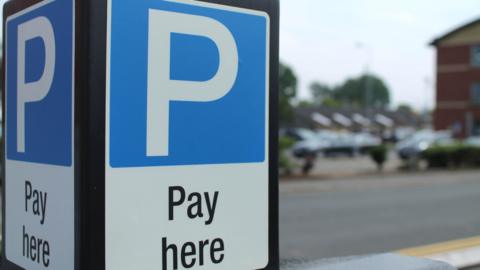 A black post with a blue 'pay here' sign. 