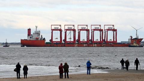 The Chinese heavy lift vessel Zhen Hua 36 is seen as it transports a new cantilever rail-mounted gantry, escorted by tug pilot boats, as it enters the River Mersey destined for a deep-water container terminal.