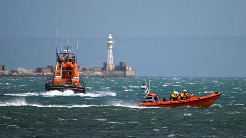 Two RNLI lifeboats travelling on the sea.