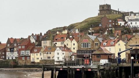 The Marine Bar and Restaurant on Marine Parade in Whitby, with the beach and sea in the foreground and a cluster of houses in the background