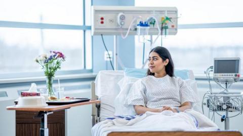 Woman in a hospital bed looking at some flowers