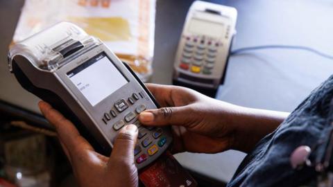 Person holding a card machine and typing in pin number